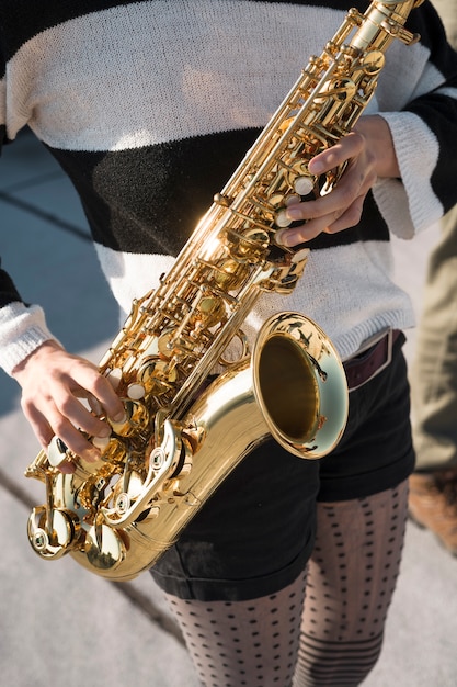 Photo gratuite gros plan sur les mains tenant le saxophone