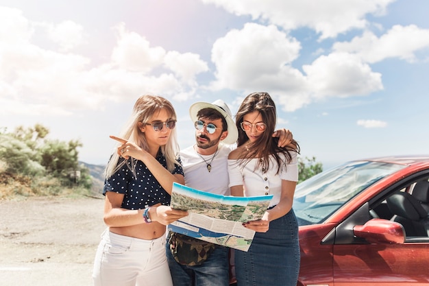 Photo gratuit groupe d&#39;amis debout près de la voiture en regardant la carte