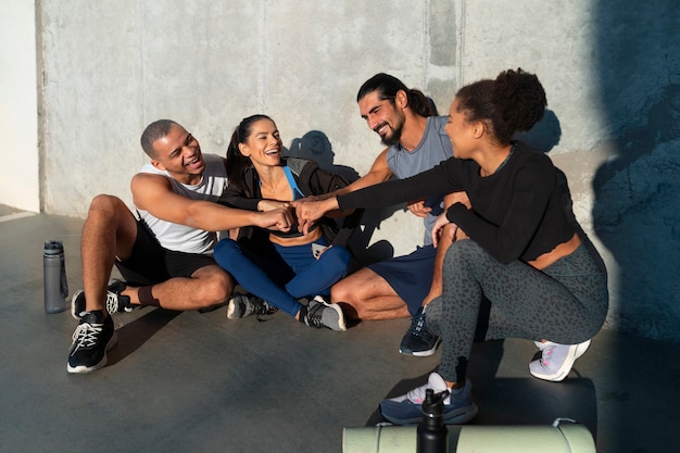 Groupe de personnes mettant leurs mains ensemble tout en faisant de l'exercice à l'extérieur