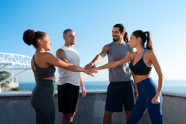 Groupe de personnes mettant leurs mains ensemble tout en faisant de l'exercice à l'extérieur