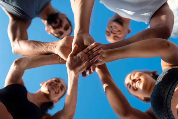 Groupe de personnes mettant leurs mains ensemble tout en faisant de l'exercice à l'extérieur