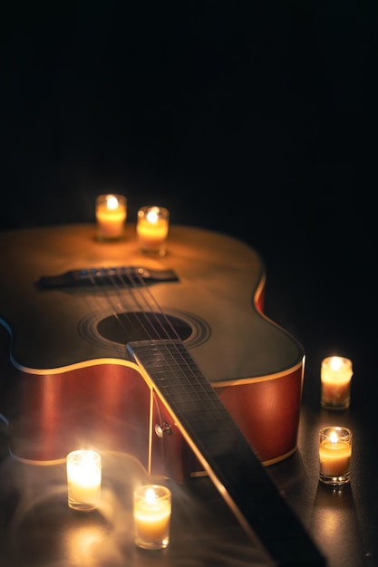 Photo gratuite guitare acoustique sur un fond noir avec des bougies