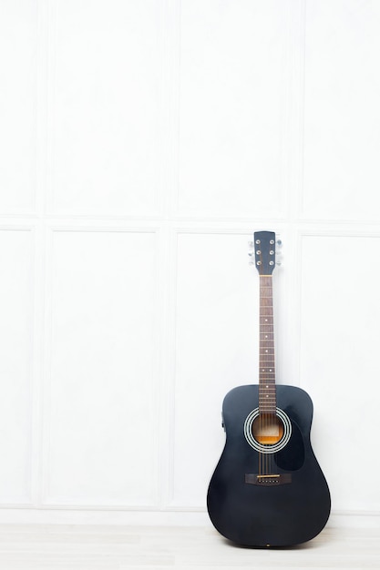 Photo gratuite guitare calée devant un mur blanc