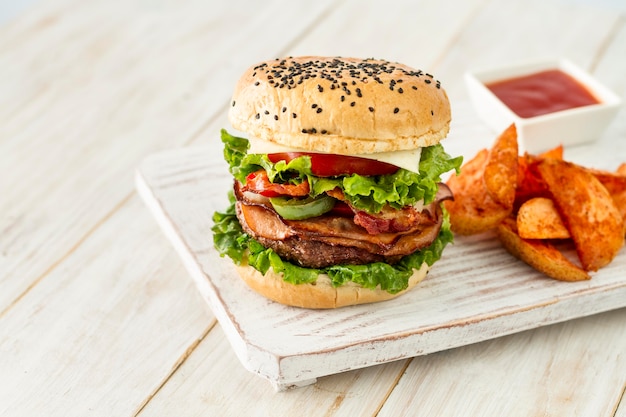 Photo gratuite hamburger savoureux avec des frites sur planche de bois