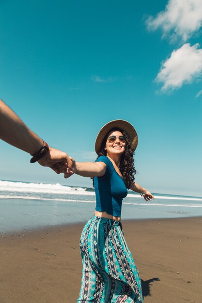 Heureuse femme menant l&#39;homme à travers le sable de la plage