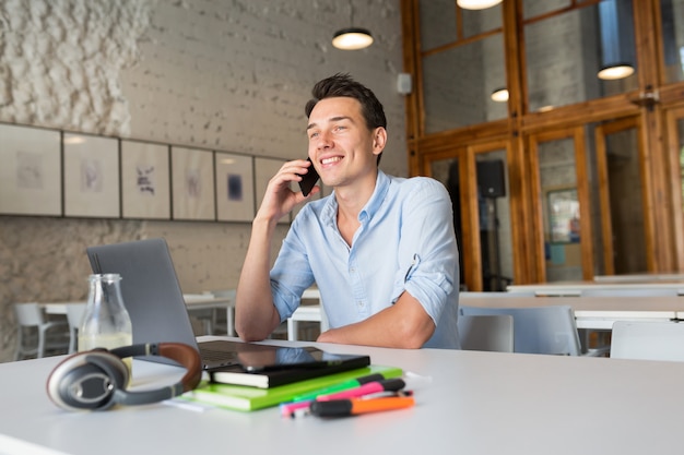 Photo gratuite heureux jeune bel homme assis dans le bureau de co-working