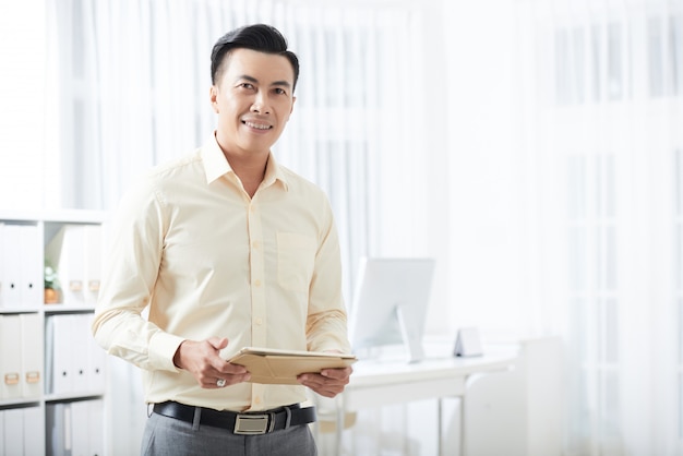 Photo gratuite homme d'affaires souriant avec tablette au bureau