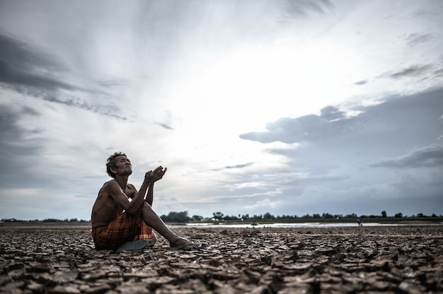 Photo gratuite un homme âgé était assis, demandant de la pluie pendant la saison sèche et le réchauffement climatique