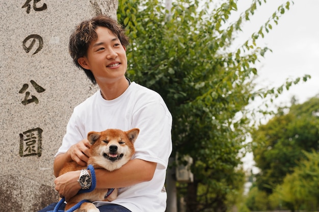 Photo gratuit homme asiatique avec son chien shiba inu à l'extérieur