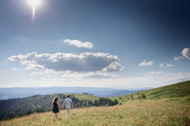 Photo gratuit homme et femme tiennent leurs mains ensemble en marchant sur la colline quelque part dans les montagnes