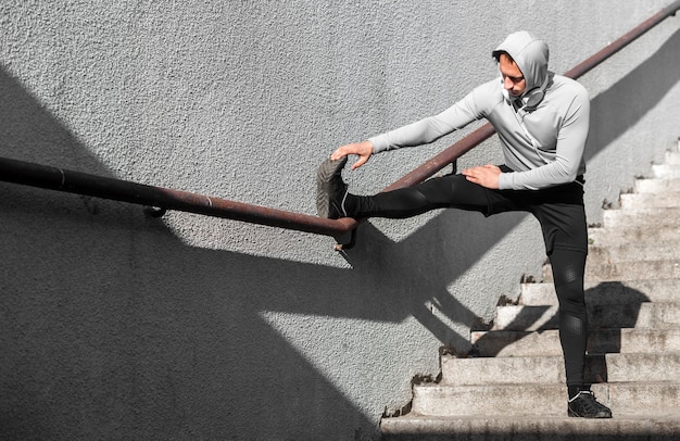 Photo gratuite homme réchauffe ses jambes à l'aide d'une balustrade