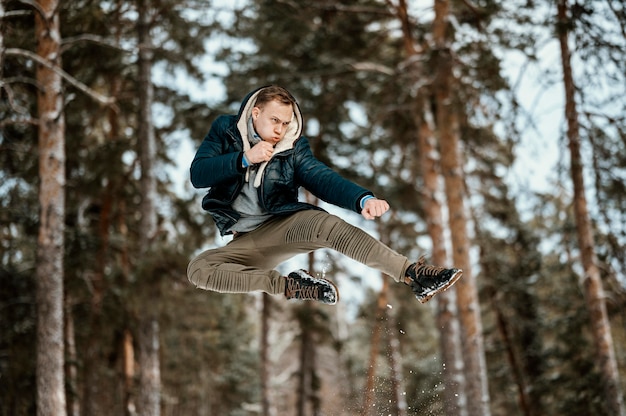 Photo gratuite homme sautant à l'extérieur dans la nature pendant l'hiver