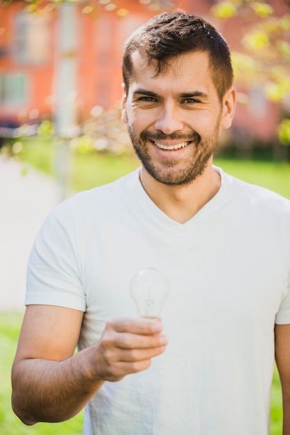 Homme souriant tenant une ampoule transparente