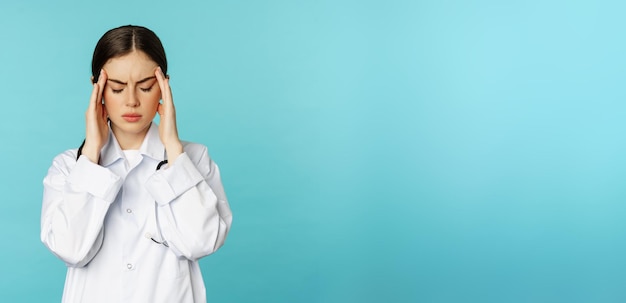 Photo gratuite image d'une femme médecin personnel médical grimaçant d'inconfort ayant des maux de tête migraine sentiment de