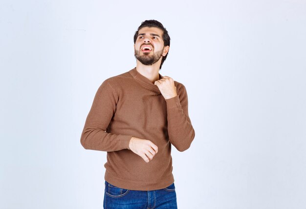 Image d'un modèle de jeune homme souriant debout et posant sur un mur blanc. photo de haute qualité