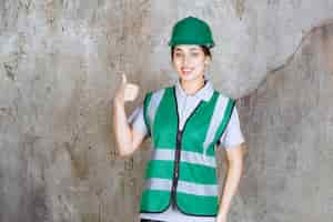 Photo gratuite ingénieure en uniforme vert et casque montrant un signe positif de la main