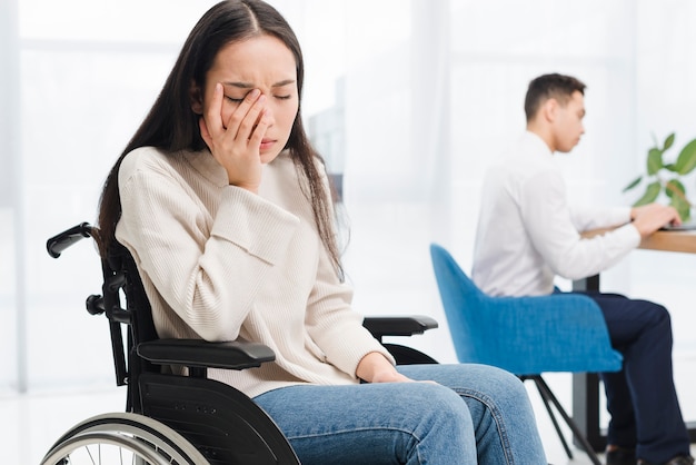 Inquiet, jeune femme, assis sur une chaise roulante, assis devant un collègue à l&#39;aide d&#39;un ordinateur portable