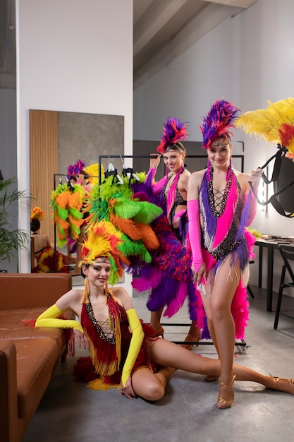 Photo gratuite interprètes féminins de cabaret posant dans les coulisses en costumes de plumes