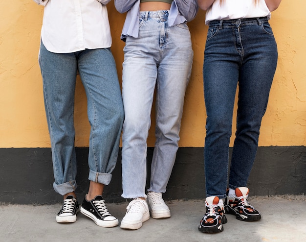 Photo gratuite jambes de femmes devant un mur jaune