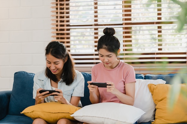 Photo gratuite jeune couple de femmes lesbiennes lgbtq utilisant un téléphone portable à la maison