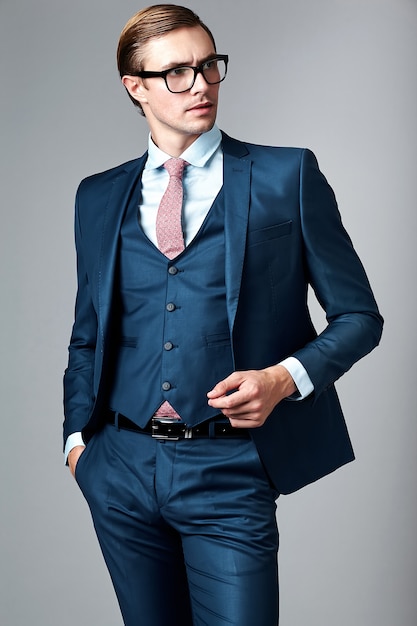 Photo gratuite jeune élégant modèle masculin beau homme d'affaires en costume bleu et lunettes à la mode, qui pose en studio