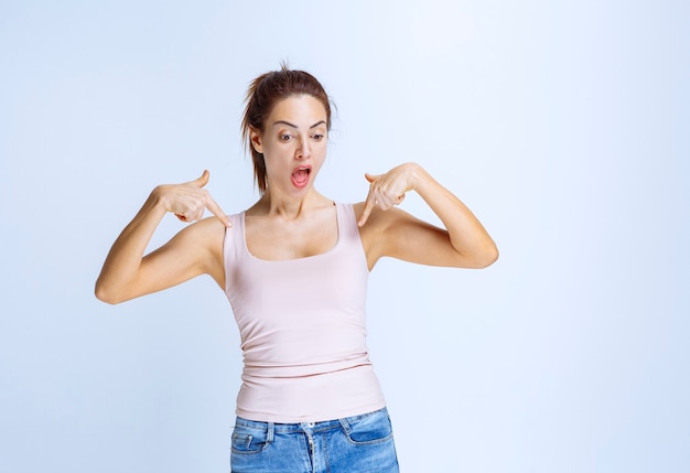 Photo gratuite jeune femme en chemise de sport pointant sur elle-même