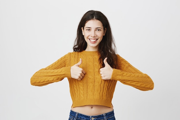 Photo gratuite jeune femme entrepreneur montrant le pouce en l'air en signe d'approbation, d'accord ou comme quelque chose, louange le choix