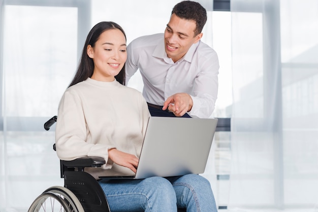 Jeune femme en fauteuil roulant travaillant avec un collègue masculin