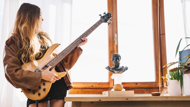 Photo gratuite jeune femme jouant de la guitare à la maison