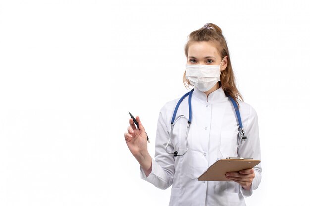 Jeune femme médecin en combinaison médicale blanche avec stéthoscope en masque de protection blanc sur le blanc