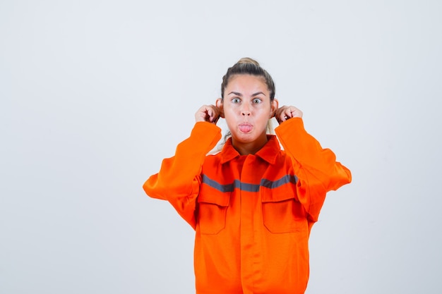 Photo gratuite jeune femme montrant le geste de singe en uniforme de travailleur et regardant bizarre, vue de face.