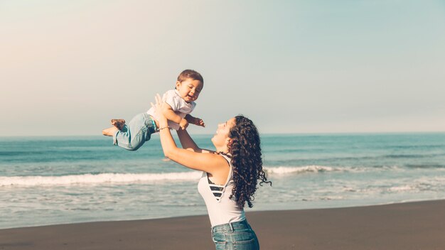 Jeune femme s&#39;amuser avec bébé sur la plage d&#39;été