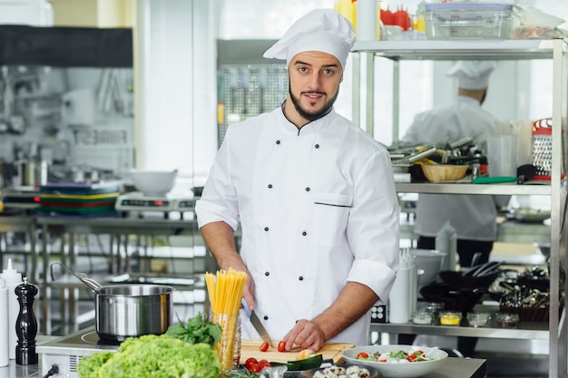 Photo gratuite jeune homme barbu sur son lieu de travail la cuisson des légumes