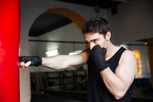 Jeune homme boxeur s'entraînant avec punchbag