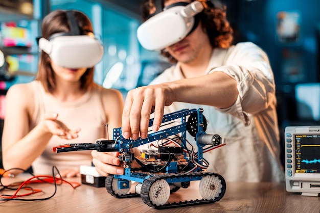 Photo gratuite jeune homme et femme dans des lunettes vr faisant des expériences en robotique dans un laboratoire robot et outils