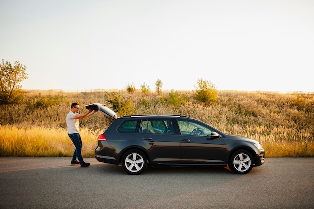 Photo gratuit jeune homme fermant le coffre de la voiture