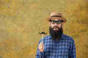 Photo gratuite jeune homme avec une longue barbe portant un chapeau et des lunettes