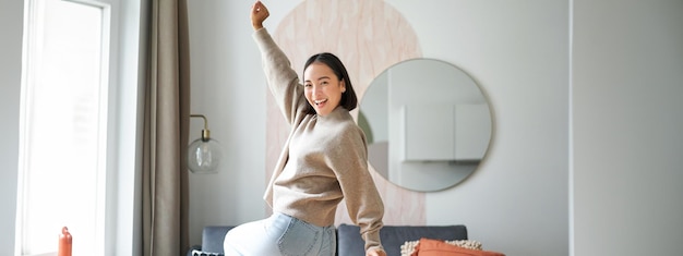 Photo gratuite jolie femme asiatique excitée dansant levant les mains en triomphe célébrant et chantant debout à