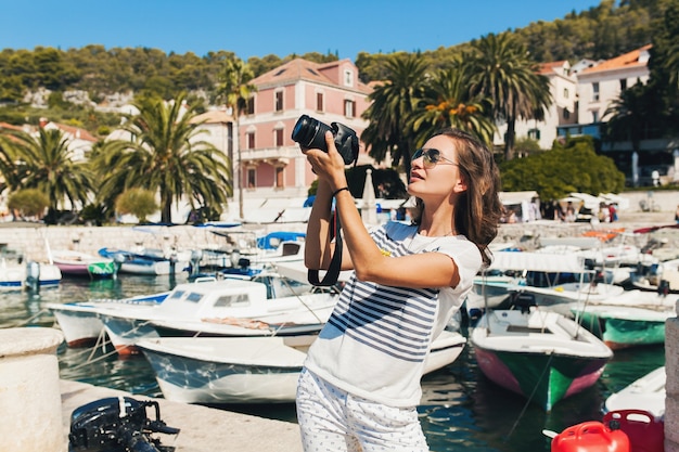 Photo gratuite jolie femme en vacances en europe au bord de la mer lors d'une croisière à prendre des photos à la caméra