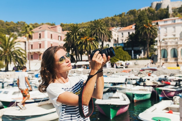 Photo gratuite jolie femme en vacances en europe au bord de la mer lors d'une croisière à prendre des photos à la caméra