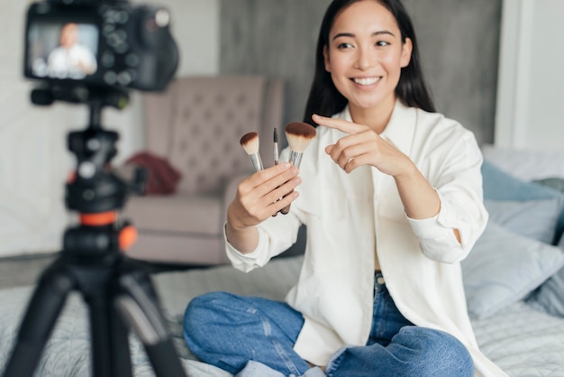 Photo gratuite jolie femme vlog sur les pinceaux de maquillage