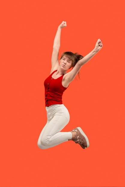 Photo gratuite liberté de mouvement. tir en l'air d'une jeune femme assez heureuse sautant et faisant des gestes sur fond de studio orange. fille runnin en mouvement ou en mouvement. concept d'émotions humaines et d'expressions faciales