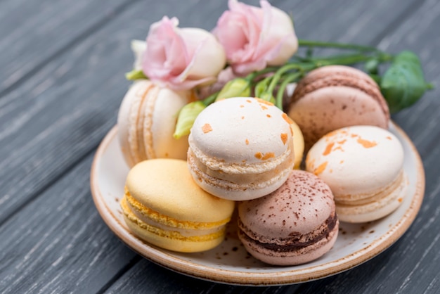 Photo gratuite macarons sur plaque avec roses