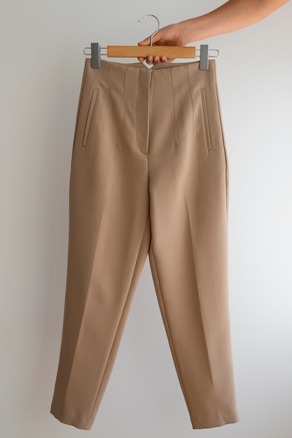 Photo gratuite la main tenant un pantalon beige brun clair