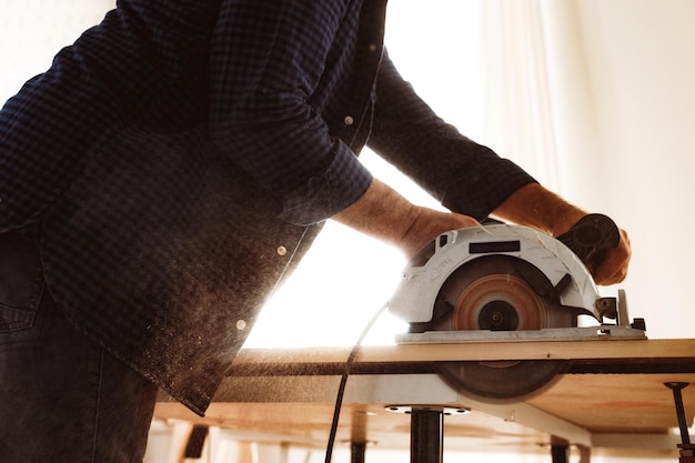 Photo gratuite mains de charpentier coupant du bois avec une scie électrique