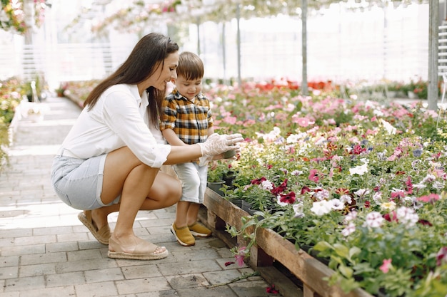 Maman et son fils plantent les fleurs dans le pot de la serre. Petit garçon en bas âge apprenant à planter dans une serre