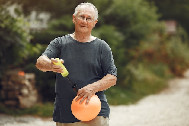 Photo gratuit man au parc d'été. grangfather utilisant une pompe pball.