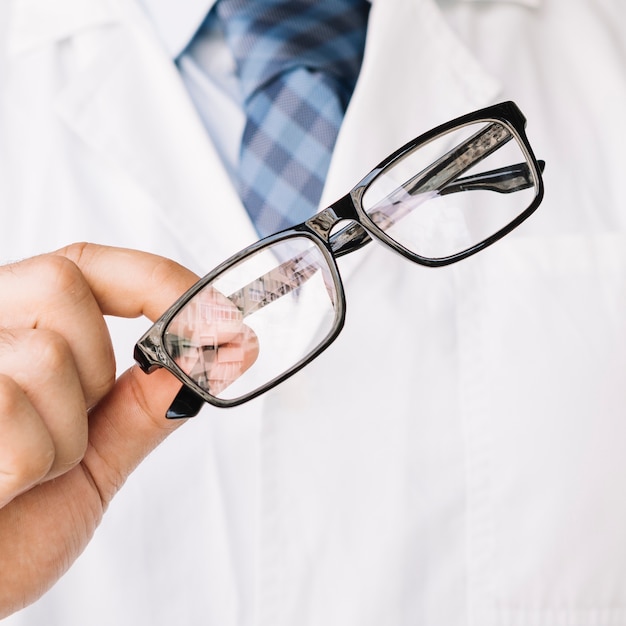 Photo gratuite médecin tenant dans une main une paire de lunettes noires