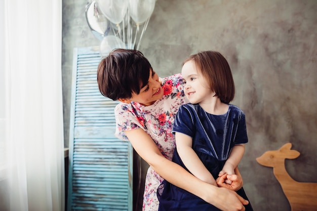 Photo gratuite la mère avec sa fille assise sur l'échelle et gardant des ballons