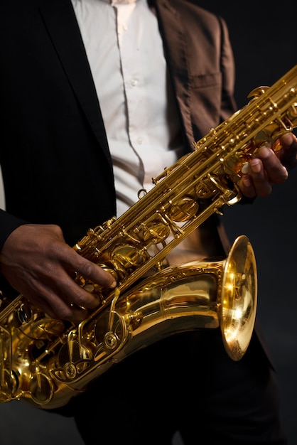 Photo gratuite musicien en costume tenant le saxophone en gros plan